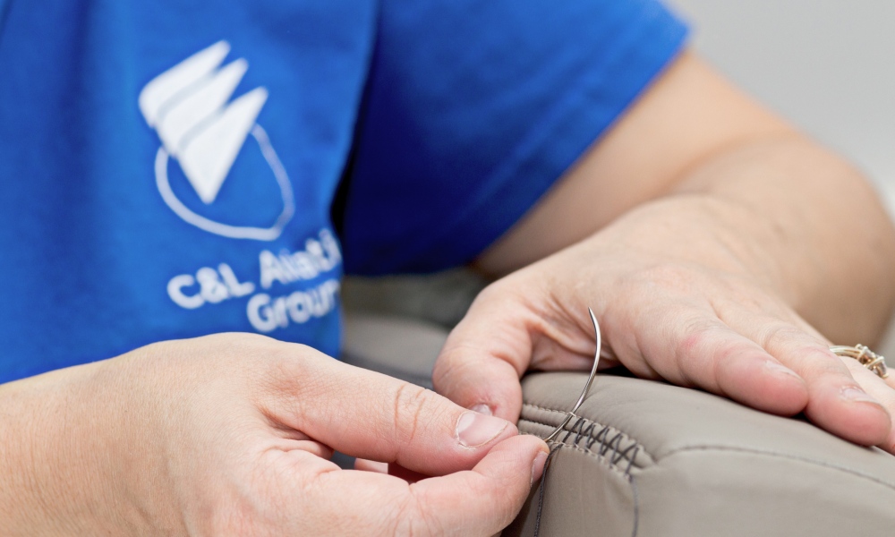 Interior regional aircraft conversion on Embraer aircraft - up close photo of worker hands adding stitching to aircraft seat