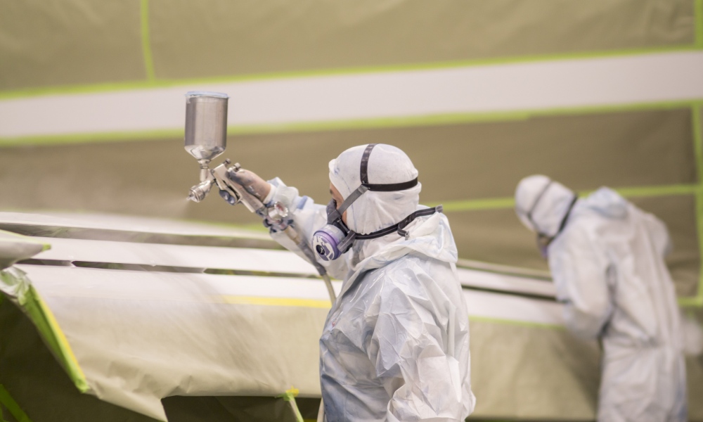 Interior regional aircraft conversion on Embraer aircraft - photo of two workers spray painting the wings of an aircraft