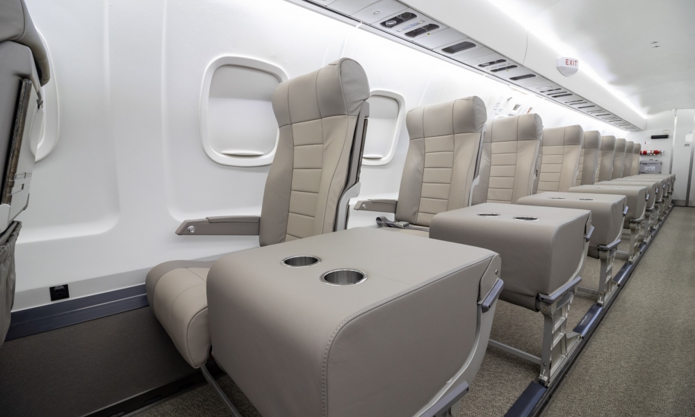 Interior regional aircraft conversion on Embraer aircraft - photo of aircraft aisle with gray seats and trays with two cup holders