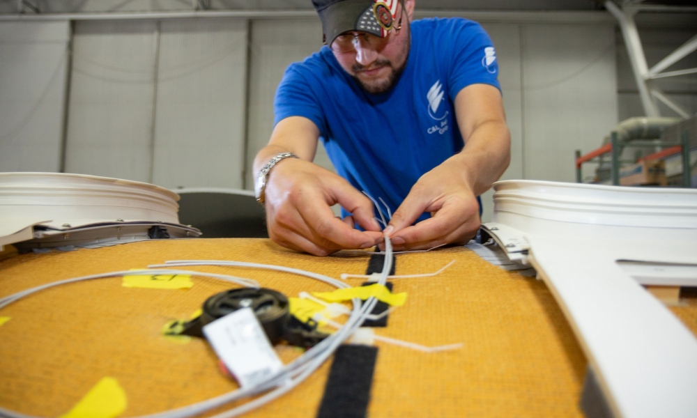 Interior regional aircraft conversion on Embraer aircraft - photo of technician installing bongiovi audio system onto top of plane