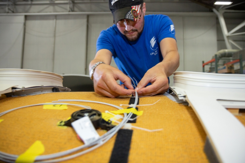 Interior regional aircraft conversion on Embraer aircraft - photo of technician installing bongiovi audio system onto top of plane