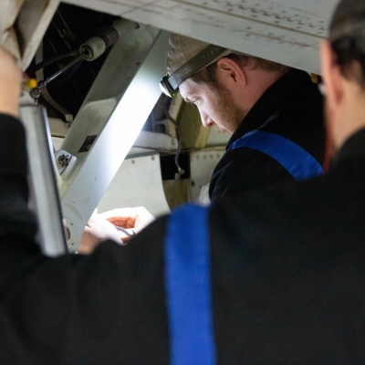 Interior regional aircraft conversion on Embraer aircraft - photo of worker with headlamp working on the interior wiring of an aircraft