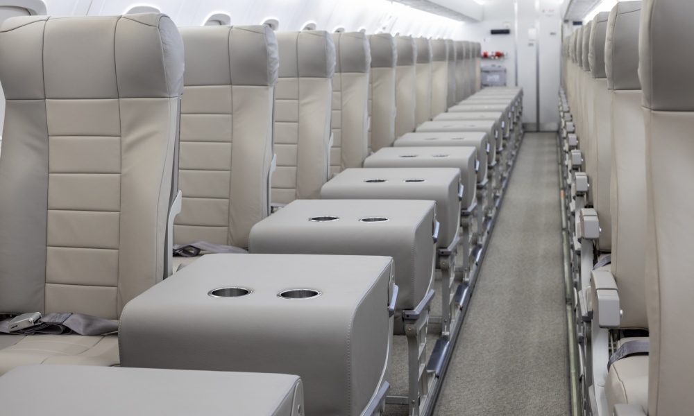 Interior regional aircraft conversion on Embraer aircraft - photo of aircraft aisle with gray seats on either side and trays with two cup holders