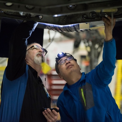 Interior regional aircraft conversion on Embraer aircraft - photo of two technicians looking in a panel on the underside of an aircraft