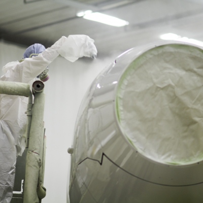 Interior regional aircraft conversion on Embraer aircraft - photo of worker spray painting the engine of an aircraft